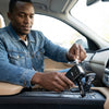 Man using a 100W Dual Socket & USB Car Charger in a car interior.