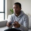 A young man using a PS3 Wireless Controller + Charging Cable while gaming at home.