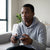 A young man using a PS3 Wireless Controller + Charging Cable while gaming at home.