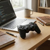 PS3 Wireless Controller + Charging Cable on a wooden table next to a laptop and notebooks