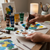 Person pouring Acrylic Paint 75ml Burnt Umber onto a palette surrounded by various other acrylic paint tubes.