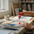 Acrylic Paint 75ml - Scarlet being poured onto a palette with paintbrushes and artwork in the background.