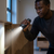 Man using a Mini Rechargeable LED Torch to illuminate a cabinet in a dimly lit room.