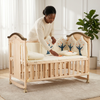 Wooden Baby Crib for Infants with Adjustable Mattress, a woman arranging bedding in a cozy nursery.