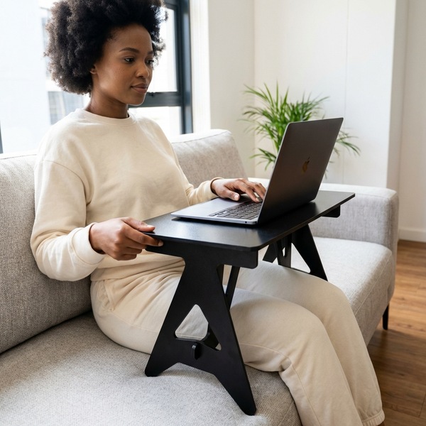 Person using a Wooden Convertible Under Desk Bed while seated on a sofa, working on a laptop.