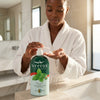Herbal Camphor Active Moisturising Body Lotion in use by a woman applying lotion in a luxurious bathroom.
