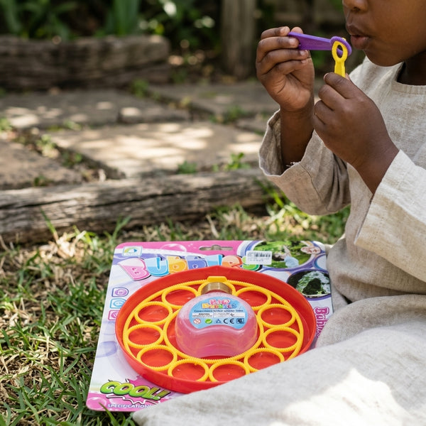 Child using Soap Bubble Maker 170ml to blow bubbles outdoors, surrounded by grass and playing joyfully.