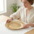 Woman setting a 13-Inch Eco-Friendly Wedding Charger Plate on a table, enhancing elegant dining presentation.