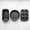 3 Piece Non Stick Bakeware Set featuring a loaf pan, round cake pan, and muffin tray on a marble surface.