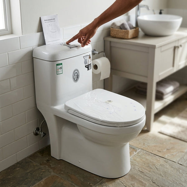 Modern Ceramic One-Piece Toilet Unit installed in a stylish bathroom with a person adjusting the flush.