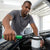 Reinforced Handcuff-Style Oil Filter Wrench Tool in use by a mechanic removing an oil filter.