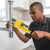 A plumber using a Heavy-Duty 55mm Steel Adjustable Pipe Wrench on a metal pipe in a modern kitchen.