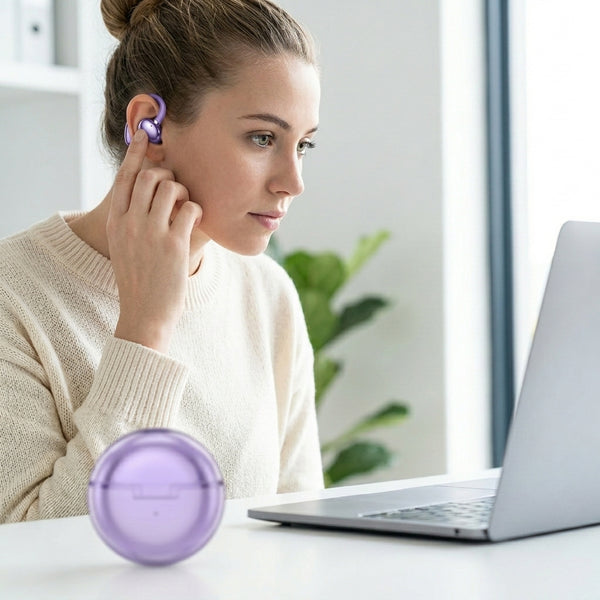Woman using Wireless Ear-Clip Sports Earbuds while working on a laptop in a bright, modern setting.