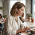 Wired In-Ear Headphones with 3.5mm Jack worn by a woman in a cafe while using a laptop.