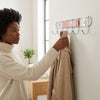 Woman using Chrome Plated 8-Hook Wall Mounted Rail to hang a coat in a stylish interior setting.