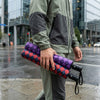 Man holding two Auto Open 3-Folding Portable Umbrellas in a city during rain.