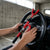 Person securing a Heavy Duty Steering Wheel to Brake Pedal Lock in a car for added security.