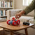 Child playing with 4WD Double-Sided Stunt Climbing RC Car on a wooden table with a game controller nearby.