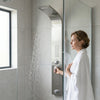Woman enjoying a shower with the Stainless Steel Rainfall Waterfall Shower Panel in a modern bathroom.