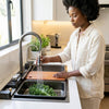 Woman washing produce in Stainless Steel Waterfall Nano Kitchen Sink with waterfall flow and digital temperature display.