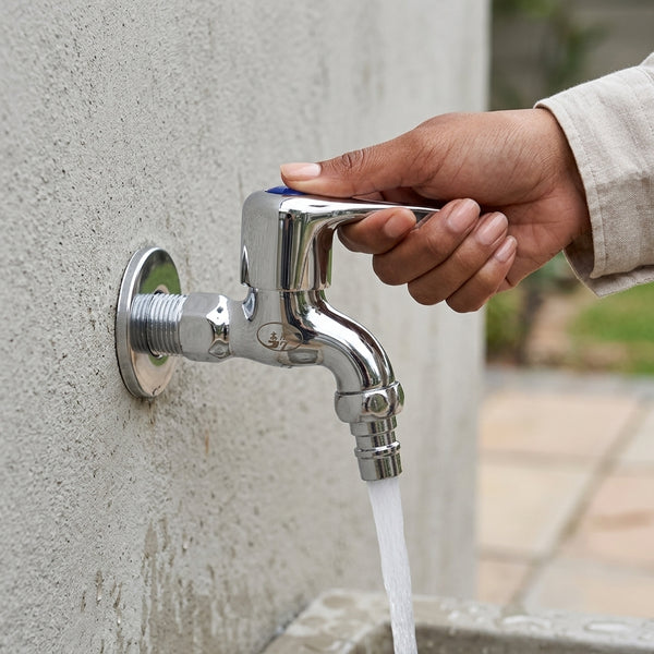 Hand turning on the Chrome Plated Brass Bib Tap with water flowing from the spout.