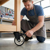 Man installing a 3-Inch Stainless Steel PU Swivel Caster on a wooden workbench.
