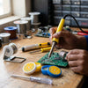 Person using a 40W Electric Soldering Iron and Welding Repair Kit on a circuit board with tools and supplies around.