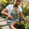 Person using a Carbon Steel Double Head Garden Hoe Fork to tend to plants in a garden pot.
