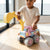Child playing with Kids Construction Excavator and Dump Truck Toy in a bright room on wooden floor.