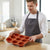 Man holding a Non-Stick 12 Cup Silicone Muffin Pan in a modern kitchen, ready for baking.