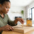 Woman installing Triangular Sawtooth Picture Hanger on a wooden frame with picture hooks in the background.