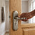 Person using the Polished Aluminum Lever Handle Door Lock on a wooden door for secure access.