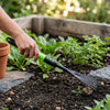 Person using a Metal Garden Lawn Rake with Telescopic Handle to maintain a garden bed.