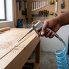 DG-10 Metal Air Dust Blower Gun in use, cleaning sawdust from a wooden workbench.