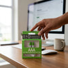 1.5V Rechargeable AAA Lithium Battery in a green packaging on a wooden desk with a computer.