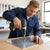 Man using HSS Tapered Hex Shank Step Drill on metal surface in workshop.