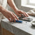 Person using Ear Wax Removal Camera Kit with LED Light next to a smartphone on a marble countertop.