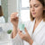 Woman applying RubySkin Repair Serum 30ml in a bathroom, showcasing skincare routine and glowing complexion.