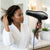 A woman in a robe using the Professional 2400W High Speed Hair Dryer to style her hair at home.
