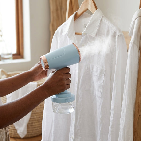 Person using 1000W Handheld Portable Garment Steamer to remove wrinkles from a white shirt.