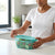 3-Piece Square Plastic Food Container with Latching Lids being opened with fresh salad inside.