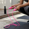 Adjustable Fitness Skipping Rope with Non-Slip Handles in pink held by a person preparing to skip.