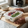 2 Section Plastic Snack Storage Container with Lid holding fresh fruits and herbs on a kitchen counter.