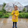 Child holding a colorful Reinforced Transparent Windproof Long Handle Umbrella while wearing a yellow raincoat in the rain.
