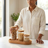 A person using a Stackable Borosilicate Glass Storage Jar with Bamboo Lid for organizing dry goods in a stylish kitchen.