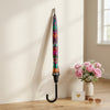 Colorful Patterned Long Handle Umbrella displayed indoors with flowers and sunglasses.