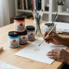 Professional Vivid Acrylic Paint 250ml displayed on a table with a hand painting creatively.