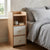 Contemporary Wooden Bedside Table with 2 Drawers beside a bed, featuring two drawers and an open shelf for storage.