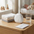 Portable White Noise Sound Machine on a bedside table with blankets and water glass for a calming sleep environment.