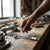 Hand reaching for a Pipe Socket Wrench L-Shaped on a workshop table surrounded by mechanical tools.